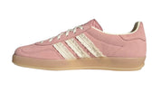 Pink Adidas sneaker with three white stripes on a light gray background